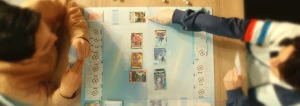 Joueurs et cartes du Gundam Card Game sur un tapis de jeu