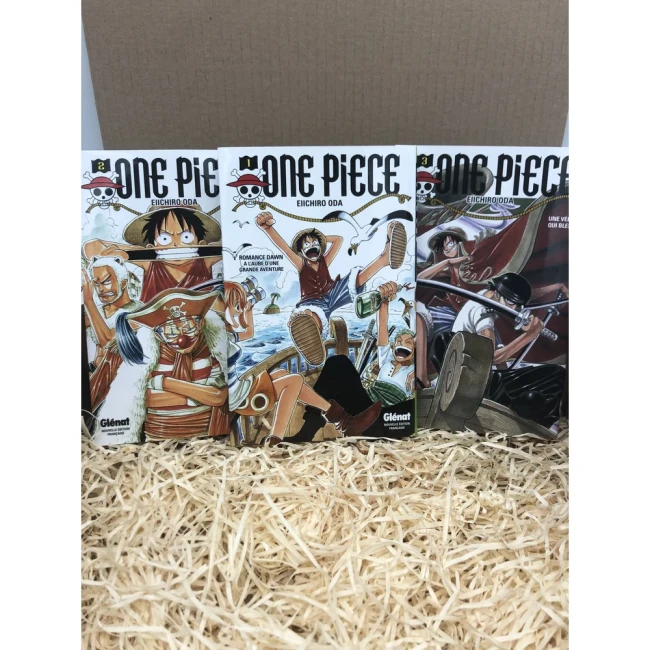 Trois tomes One Piece présentés dans une boîte ouverte