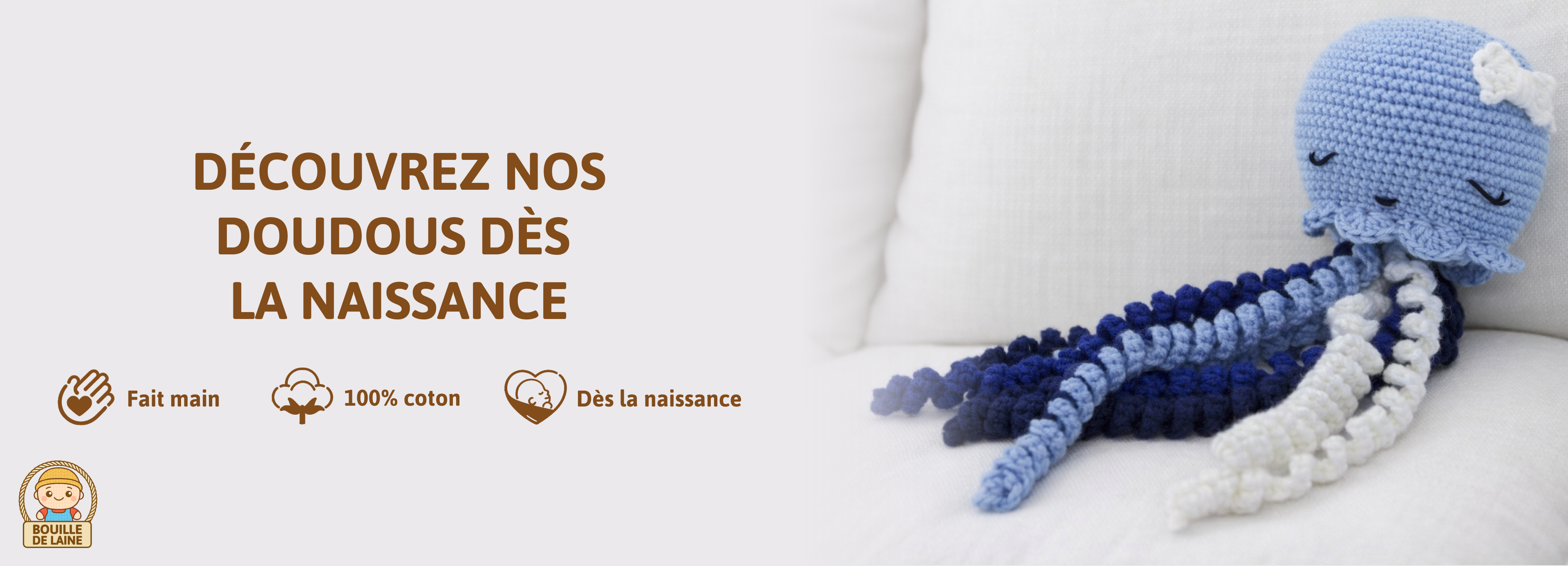 Un Doudou dès la naissance en coton fait au crochet, représentant une méduse. Le doudou est dans une variété de teintes bleues et est orné d'un nœud papillon sur la tête. Il est endormi paisiblement sur un canapé blanc.