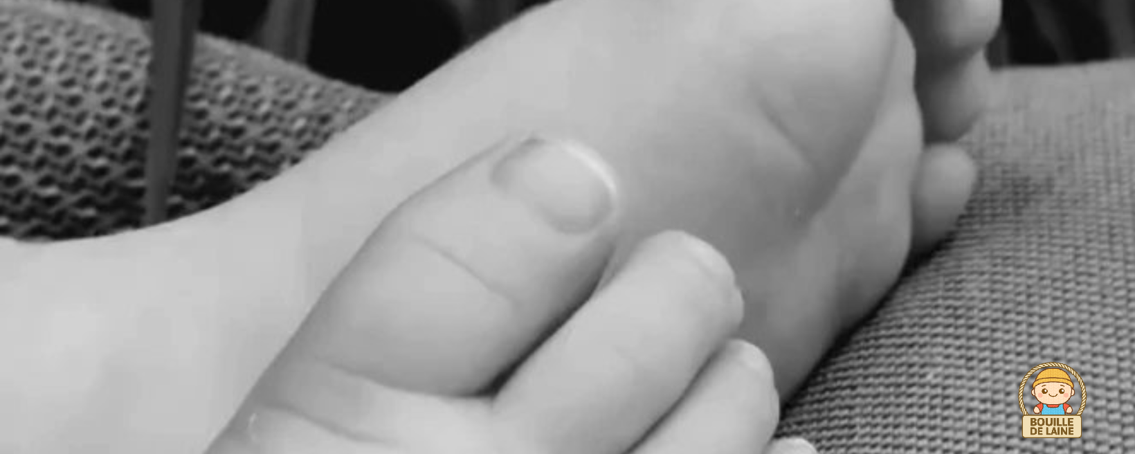 Gros plan en noir et blanc sur les petits pieds d’un bébé, illustrant l’univers doux et artisanal de Bouille-de-laine