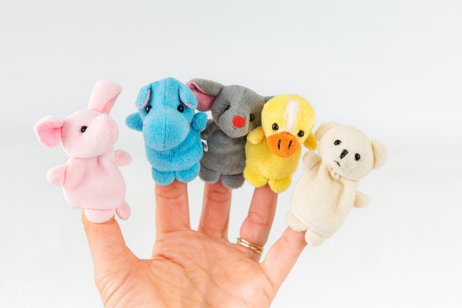 Cinq marionnettes doigt en tissu représentant des animaux, portées sur une main, sur fond matelassé blanc.