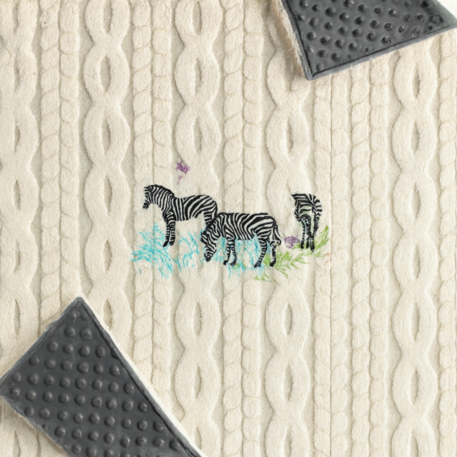 Détail brodé de trois zèbres et papillons sur couverture bébé artisanale