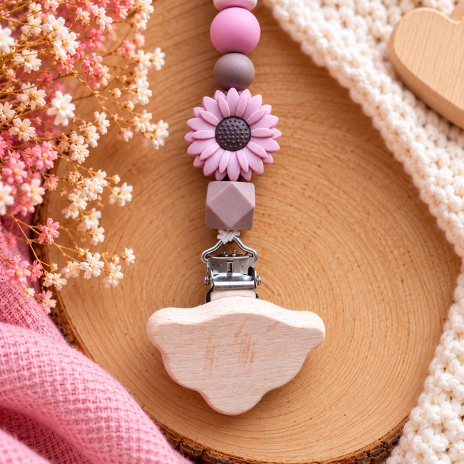 Gros plan de la pince en bois naturel et des perles rose poudré de l’attache-sucette artisanale
