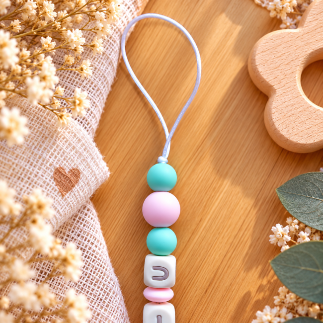 Boucle en cordon blanc et perles rondes en silicone rose et vert menthe sur une attache sucette artisanale