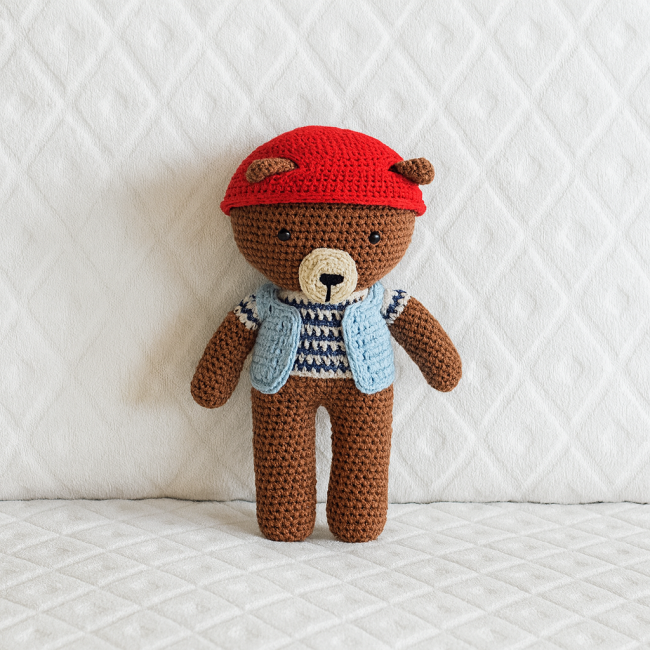 Ours crocheté portant un casque rouge, un gilet bleu et un pull rayé bleu marine et blanc