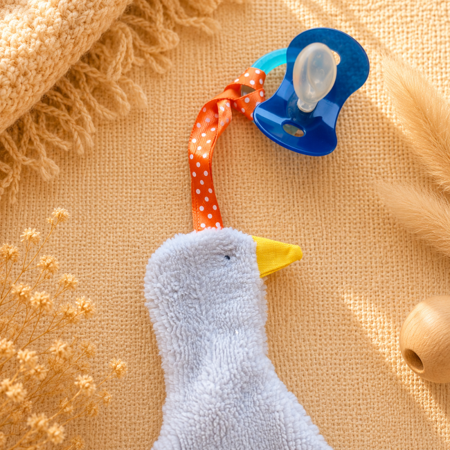 Attache-sucette bébé en bambou avec ruban orange à pois blancs et sucette bleue