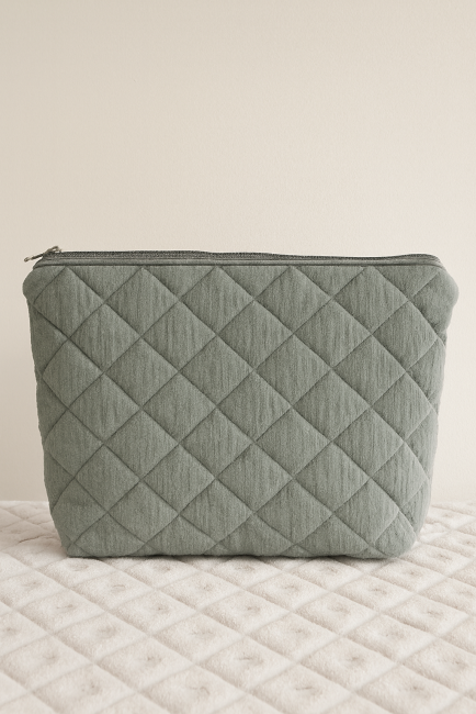 Trousse artisanale en tissu matelassé verte, posée sur fond assorti
