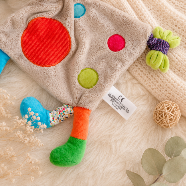 Détail des textures et étiquette du doudou girafe multicolore