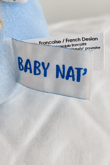 Étiquette de marque BABY NAT' sur un doudou bleu pour bébé