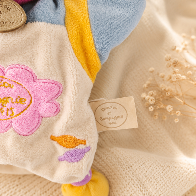 Détail de la broderie et de l'étiquette Doudou et Compagnie sur la marionnette vache