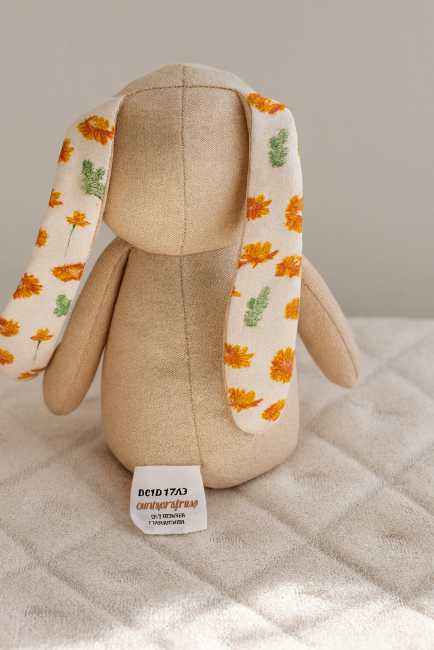 Doudou lapin fait main vu de dos, tissu beige et oreilles fleuries orange et vert