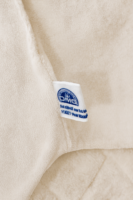 Étiquette DMC bleue sur tissu blanc cassé, mention 