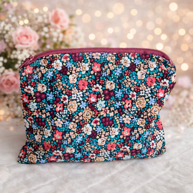 Trousse artisanale fleurie – vue décorative Trousse artisanale fleurie posée sur surface bois clair, décorée de fleurs et lumière douce en arrière-plan.