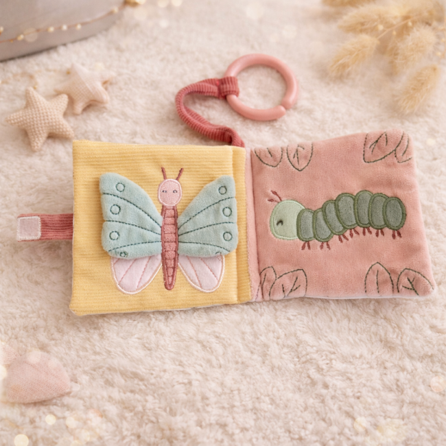 Livre d’éveil en tissu avec papillon pastel et chenille verte brodée, posé sur surface douce