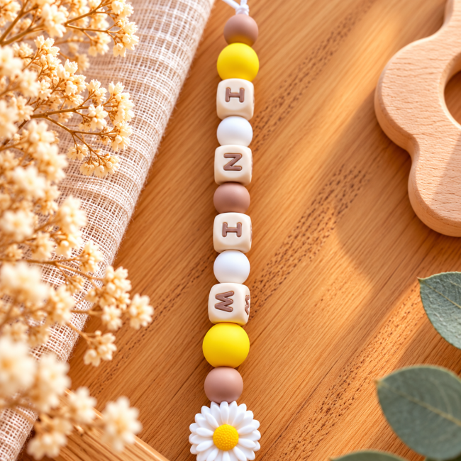 Détail des perles lettres blanches et des perles silicone jaunes et marron de l’attache sucette artisanale