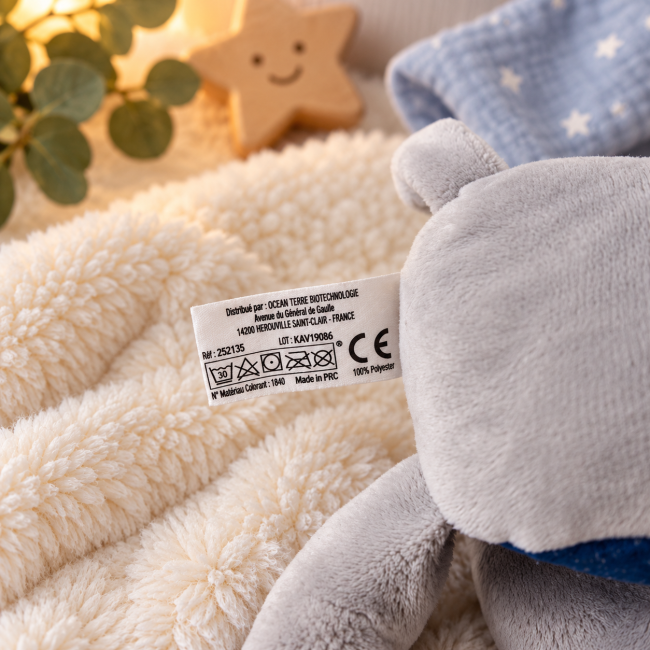 Étiquette du doudou gris indiquant 100 pour cent polyester et lavage à 30 degrés