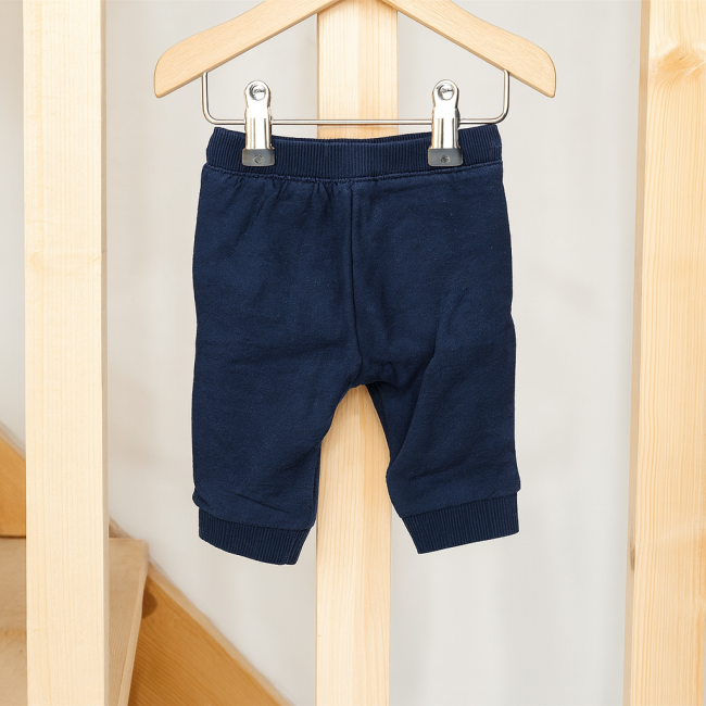 Pantalon bébé bleu marine à taille élastique et bas resserrés, suspendu sur cintre