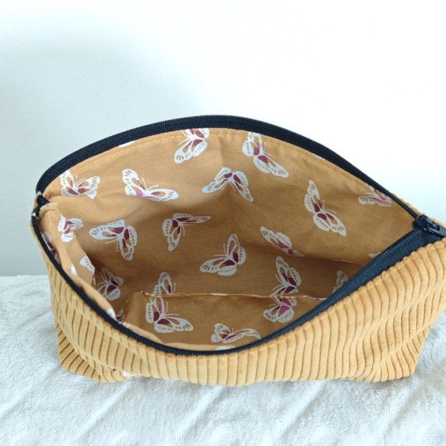 Intérieur de la trousse en tissu moutarde avec motifs papillons blancs, roses et violets