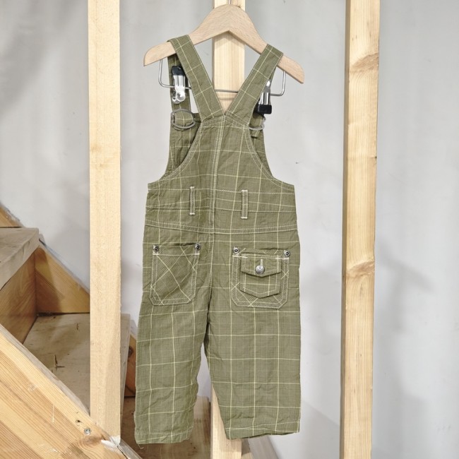 Salopette bébé 12 mois La Compagnie des Petits - à carreaux verts, suspendue sur fond bois, seconde main