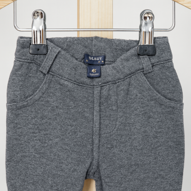 Pantalon enfant gris foncé avec poches avant et taille élastique, suspendu sur cintre bois