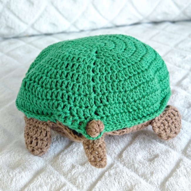 Tortue en crochet avec carapace verte et membres bruns sur fond blanc