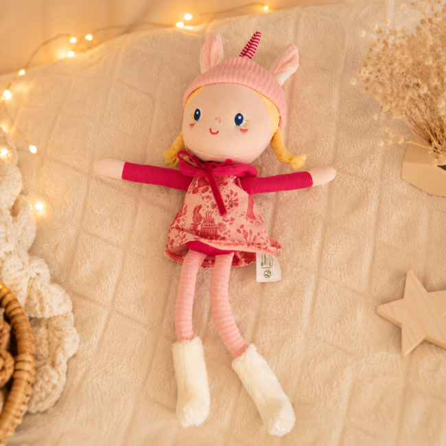 Doudou licorne Liliputiens seconde main Poupée chiffon licorne rose Liliputiens allongée sur un plaid doux pour bébé