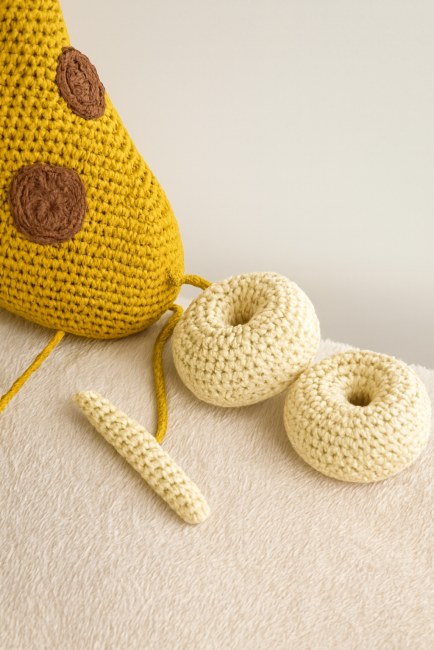  Anneaux en crochet crème et pièce allongée sur fond doux, détail du jouet girafe