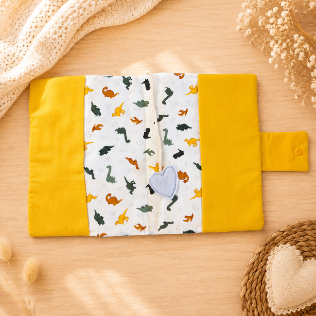 Protège-carnet de santé bébé ouvert avec tissu dinosaures et marque-page cœur