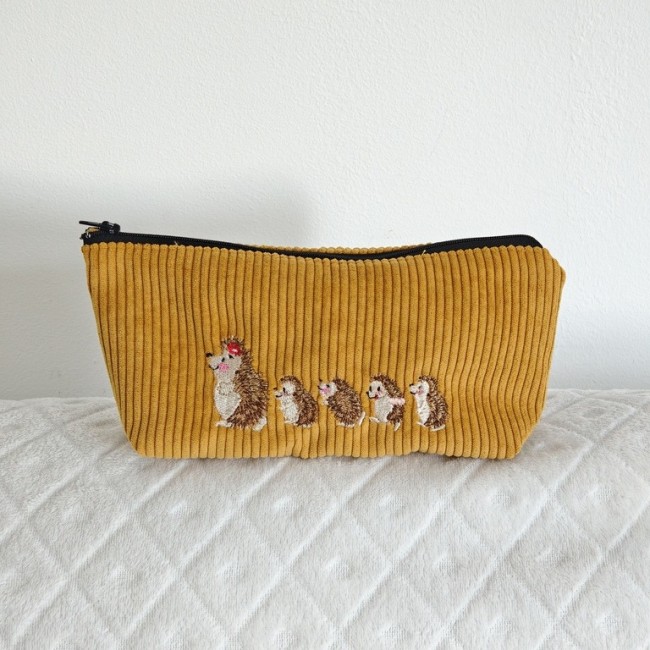 Trousse en velours côtelé jaune moutarde brodée de cinq hérissons, dont un avec un motif rouge