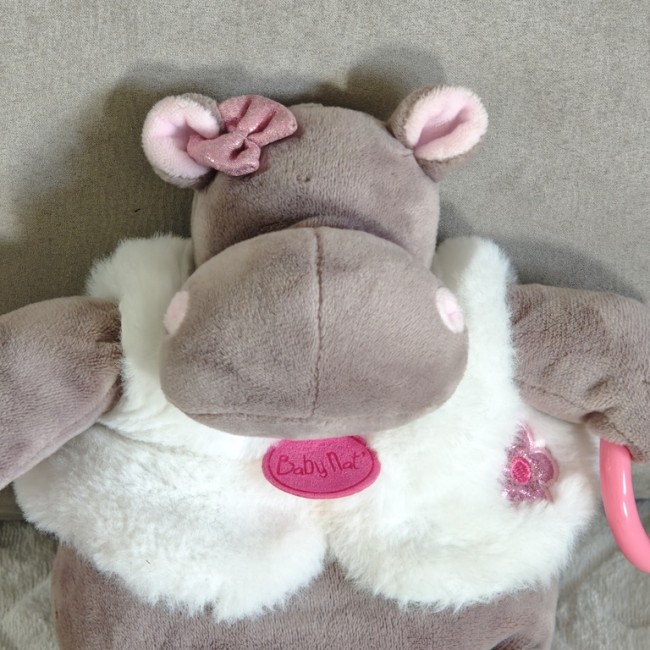 Doudou hippopotame Baby Nat’ avec veste blanche et grelot, détail du visage et du torse.