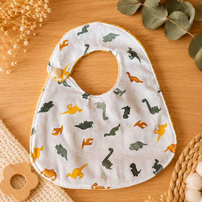 Bavoir T2 bébé motif dinosaures côté imprimé Bavoir bébé T2 en tissu imprimé dinosaures multicolores sur fond clair