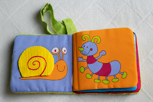 Pages d’un livre en tissu avec escargot jaune et chenille multicolore brodés