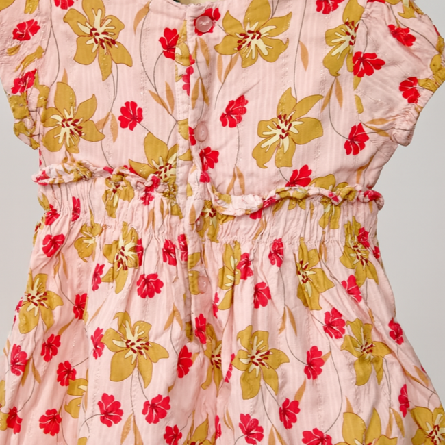 Détail de robe fille rose fleurie, boutons et fronces à la taille