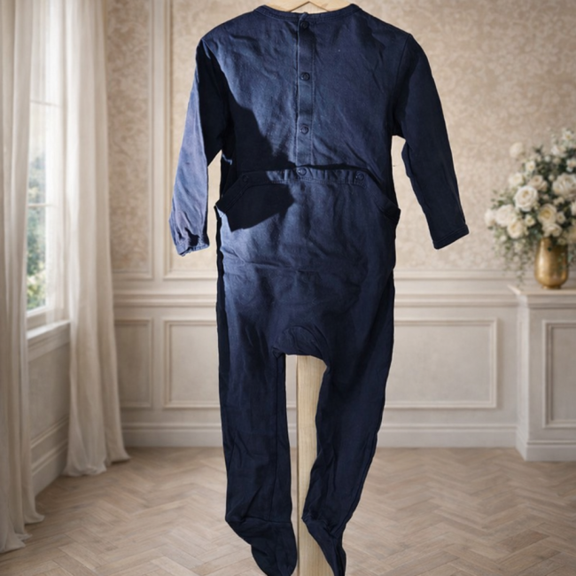 Pyjama bleu marine bébé en coton, manches longues, boutons au dos, présentée sur cintre.