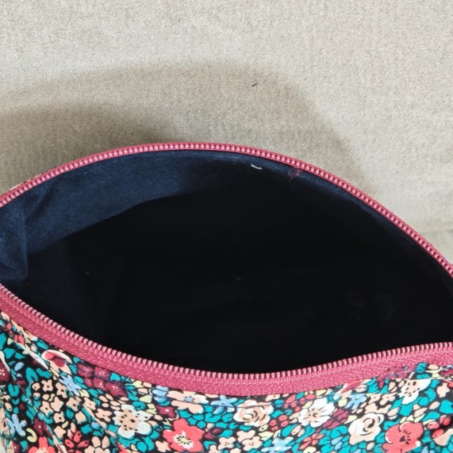 Trousse artisanale fleurie – intérieur et ouverture Trousse artisanale fleurie ouverte, montrant la doublure intérieure foncée et la fermeture zippée rouge.