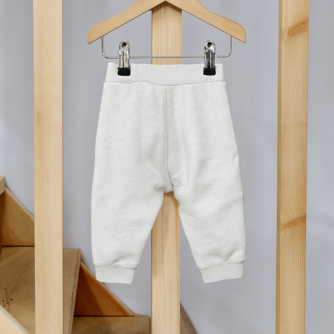 Pantalon bébé confortable, taille élastique et bas côtelés, présenté sur cintre bois