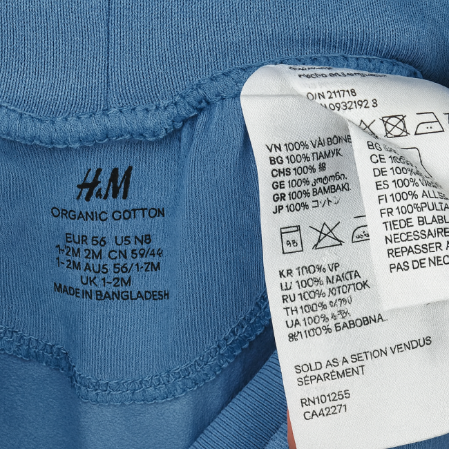 Étiquette intérieure du pantalon bébé H&M en coton biologique avec instructions d’entretien