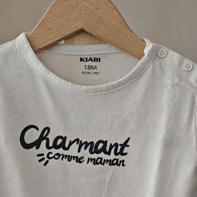 Tee-shirt bébé KIABI 18 mois “Charmant comme maman” présenté dans une ambiance douce et lumineuse