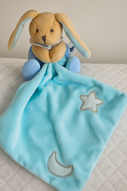 Doudou lapin bleu tenant une couverture brodée lune et étoile