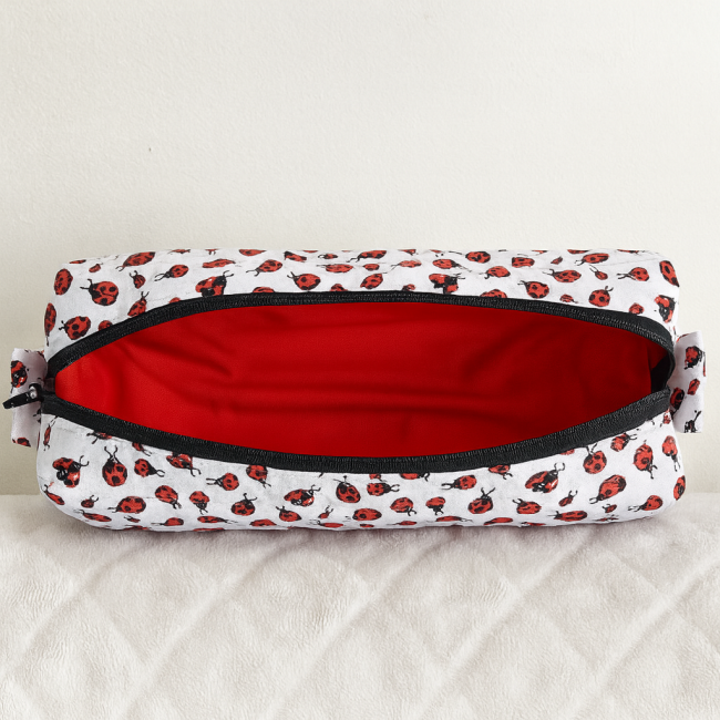 Trousse artisanale ouverte avec doublure rouge et motif coccinelles rouges et noires.
