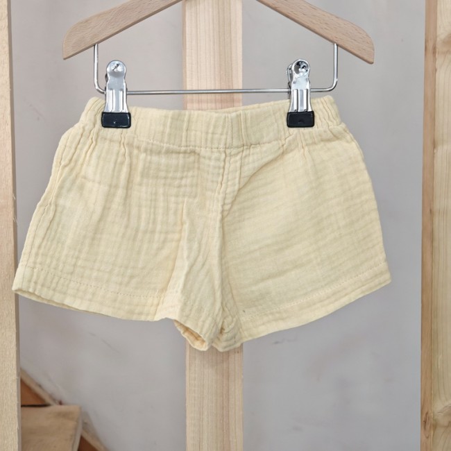 Short léger pour enfant de 2 ans - coton doux jaune pâle Short enfant jaune pâle en tissu léger avec taille élastique, présenté sur cintre en bois