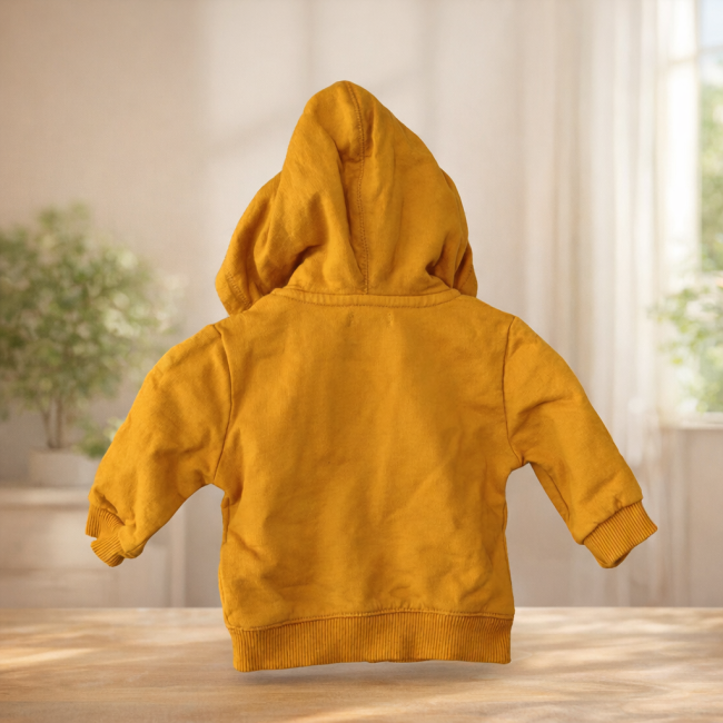 : Sweat à capuche enfant moutarde présenté dans une mise en scène chaleureuse