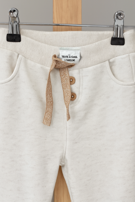 Pantalon bébé en maille douce, taille à cordon, trois boutons bois, poches et bas côtelés