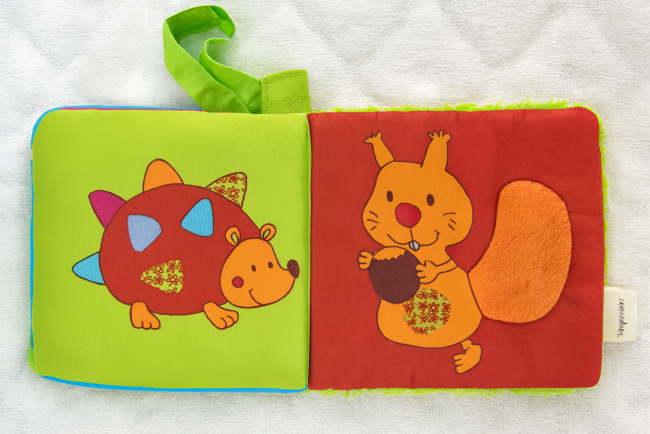 Livre en tissu pour bébé avec herisson coloré et écureuil tenant un gland