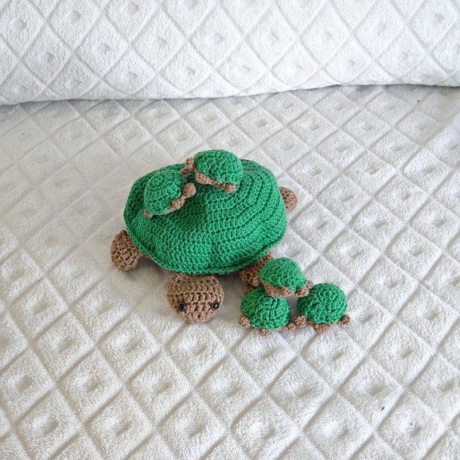 Tortue crochetée artisanale avec ses bébés sur une couverture blanche