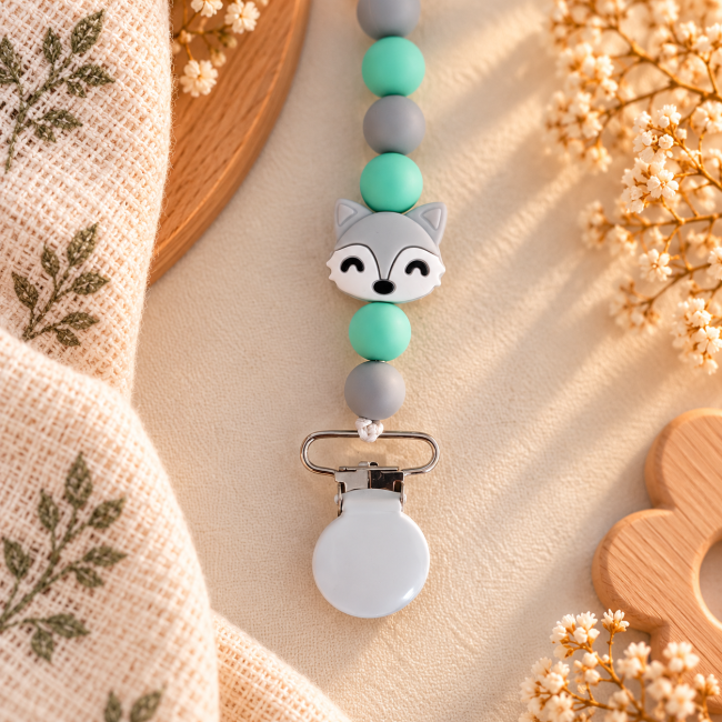Gros plan sur la perle décorative renard gris et blanc entourée de perles en silicone vert menthe