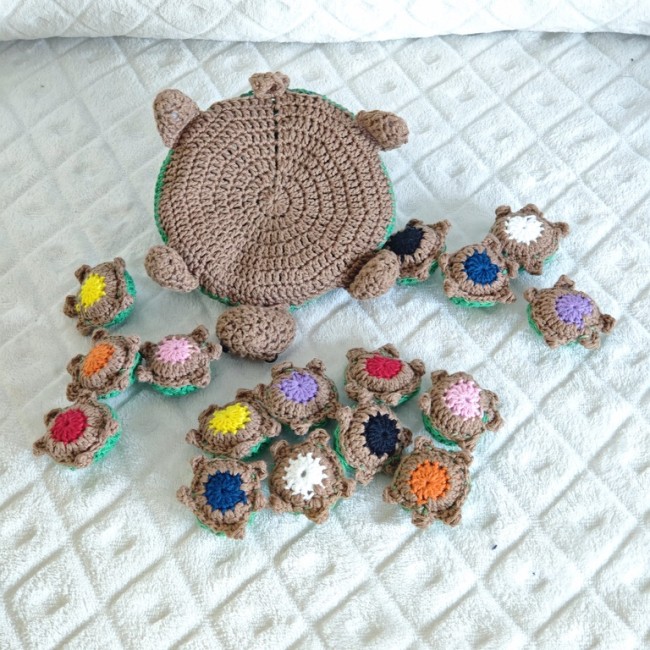 Tortue artisanale entourée de bébés crochetés avec ventre brun et centre coloré