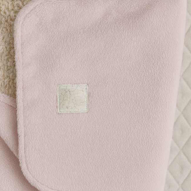 Détail tissu rose pelucheux avec patch blanc usé – gigoteuse bébé seconde main