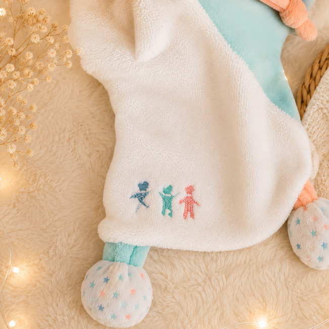 Broderie doudou ours pastel bébé Détail de la broderie colorée sur le doudou marionnette ours de seconde main