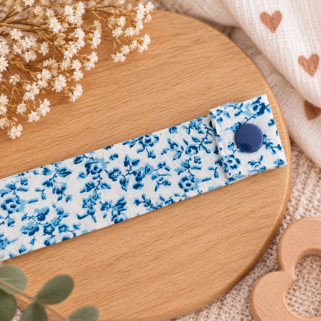 Détail du tissu blanc à petites fleurs bleues de l'attache sucette